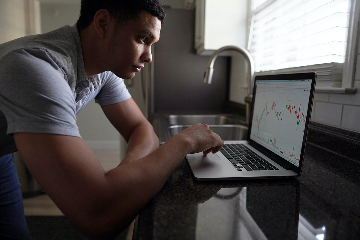 man evaluating stocks on laptop